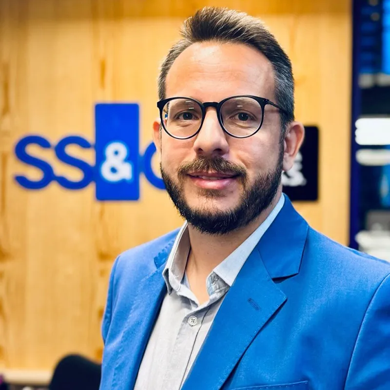 Pessoa de óculos sorrindo em ambiente corporativo